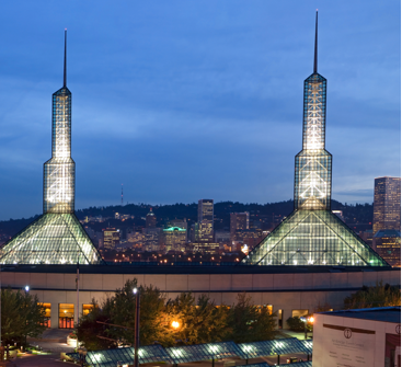 An exterior photo of the Oregon Convention Center’s glass towers at night